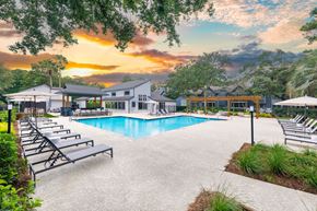 Mt Pleasant apartment for rent - A pool area with sun loungers and a building in the background during sunset.