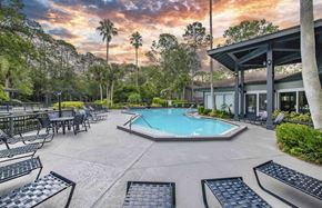 Jacksonville apartment for rent - a pool with lounge chairs and a building with a resort style pool