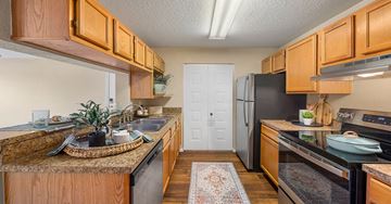 Jacksonville apartment for rent - A kitchen with wooden cabinets and a black refrigerator.
