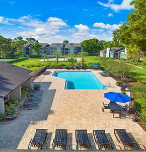 Jacksonville apartment for rent - an aerial view of a pool and patio with chairs and an umbrella