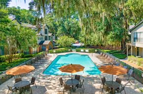 Savannah apartment for rent - the pool is surrounded by tables with umbrellas and trees