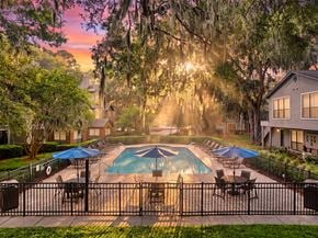 Savannah apartment for rent - A pool surrounded by trees and a fence with sunlight shining through the branches.