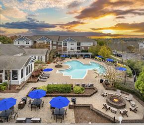 Huntersville apartment for rent - A sunset view of a pool area with a fire pit and lounge chairs.