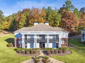Midlothian apartment for rent - A house with a grey roof and a white door is surrounded by green grass and trees.