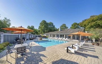 Hampton apartment for rent - A large outdoor patio with a pool and orange umbrellas.