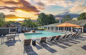 Hampton apartment for rent - a swimming pool with chairs and a sunset in the background