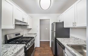 Fredericksburg apartment for rent - A kitchen with a black fridge and stove top oven.