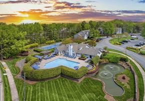 Matthews apartment for rent - an aerial view of a pool and yard with a house and a sunset