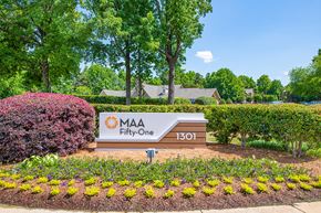 Matthews apartment for rent - a sign in front of a park with flowers and trees