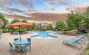Matthews apartment for rent - A pool area with a table and chairs and a red umbrella.