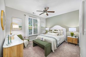 Matthews apartment for rent - A bedroom with a large bed and a green bench.