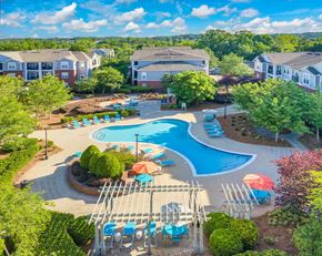 Matthews apartment for rent - A swimming pool surrounded by trees and chairs.