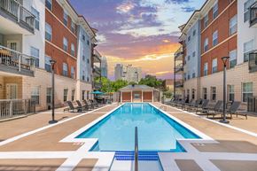 Charlotte apartment for rent - A swimming pool surrounded by lounge chairs and apartment buildings.