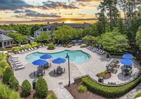 Morrisville apartment for rent - an aerial view of a pool with chairs and umbrellas at sunset