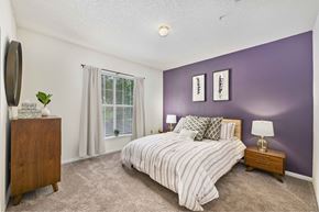 Raleigh apartment for rent - A bedroom with a bed, nightstand, and a plant.