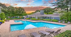 Raleigh apartment for rent - A large outdoor swimming pool surrounded by lounge chairs and trees.