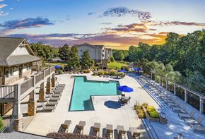 Raleigh apartment for rent - a swimming pool with lounge chairs and umbrellas at sunset