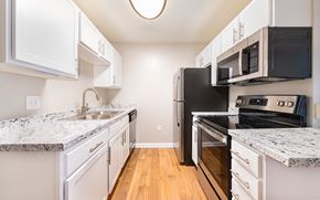 Raleigh apartment for rent - an empty kitchen with white cabinets and black appliances