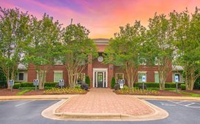 Cary apartment for rent - a brick building with trees in front of it and a parking lot
