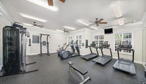 Raleigh apartment for rent - a gym with cardio machines and weights on the floor and windows