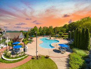 Nashville apartment for rent - an aerial view of a swimming pool with umbrellas and patio furniture at dusk