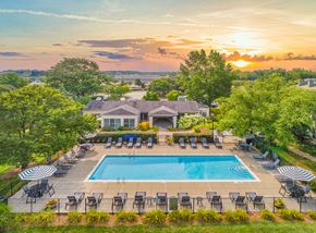 Lexington apartment for rent - an aerial view of a pool with chairs and a house in the background at sunset