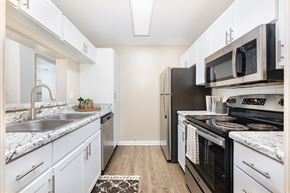 Huntsville apartment for rent - A kitchen with white cabinets and a black refrigerator.