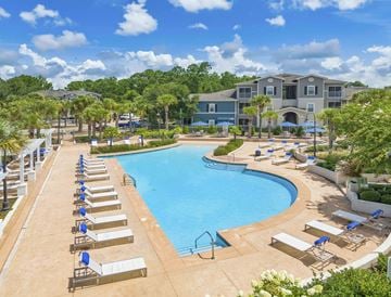 Gulf Shores apartment for rent - A large swimming pool with sun loungers and a building in the background.