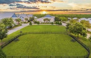 Orange Beach apartment for rent - A sunset view of a large grassy field with a fence and a few trees.