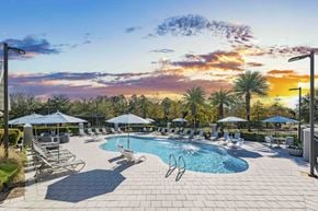 Orange Beach apartment for rent - A large outdoor swimming pool surrounded by lounge chairs and umbrellas.