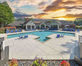 Memphis apartment for rent - A large outdoor swimming pool surrounded by a patio area with chairs and a building in the background.