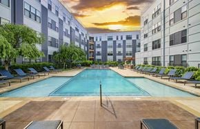 Kansas City apartment for rent - a swimming pool in front of an apartment building at sunset