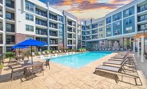 Nashville apartment for rent - an outdoor pool with chairs and umbrellas in front of an apartment building