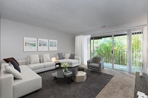 Danville apartment for rent - A carpeted, large living room with big white couch, coffee table, rug and sliding glass doors out to a big balcony.