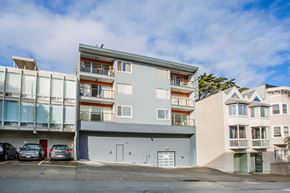 San Francisco apartment for rent - A grey apartment building with a parking lot in front.