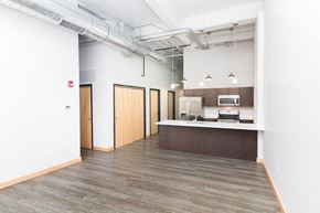 Sioux City apartment for rent - an empty living room with a kitchen and exposed ceilings