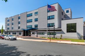 Wilmington apartment for rent - A grey building with a blue awning and an American flag on top.