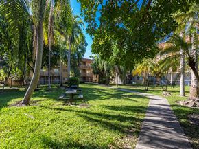 Miami apartment for rent - a park with a picnic table and trees in front of a building