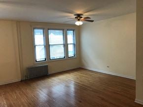 Chicago apartment for rent - an empty living room with a ceiling fan and a window