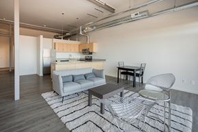 Detroit apartment for rent - A modern living room with a grey sofa, a glass table, and a striped rug.