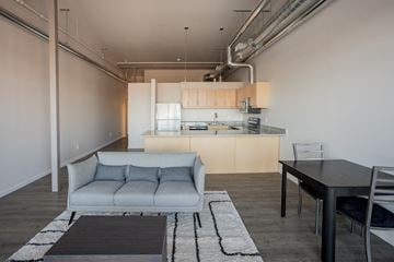 Detroit apartment for rent - A modern living room with a grey sofa and a black table.