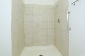 Las Vegas apartment for rent - A white tiled shower stall with a drain in the middle.