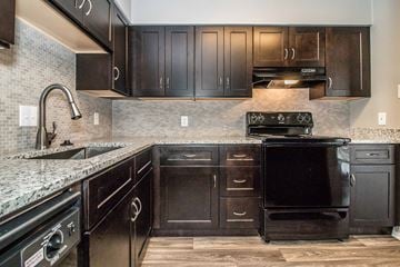 Hurst apartment for rent - a kitchen with black appliances and dark wood cabinets
