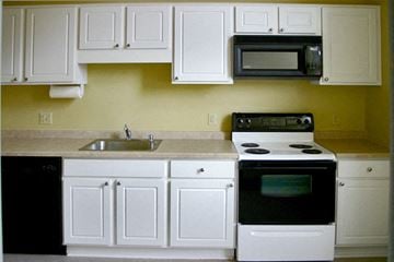 Oshkosh apartment for rent - a kitchen with white cabinets and black appliances and a sink