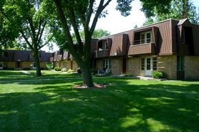 Oshkosh apartment for rent - a group of houses on a lawn with trees