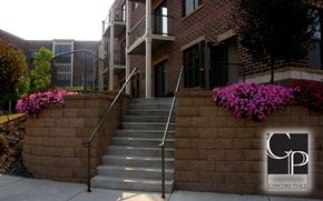 Oshkosh apartment for rent - a stone wall with stairs in front of a building with purple flowers