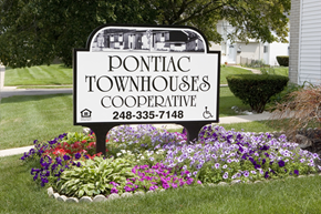 Pontiac townhouse for rent - a sign townhouses cooperative in front of a garden