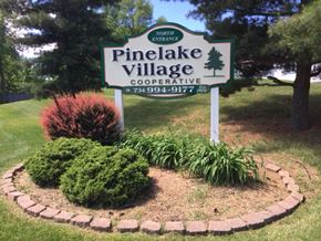 Ann Arbor townhouse for rent - a sign for the pine lake village cooperative in the middle of a garden