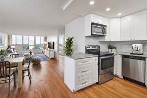 Mississauga apartment for rent - an open kitchen with stainless steel appliances and a dining room with a table