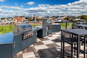Washington apartment for rent - a rooftop barbecue area with tables and bbqs and a city in the background